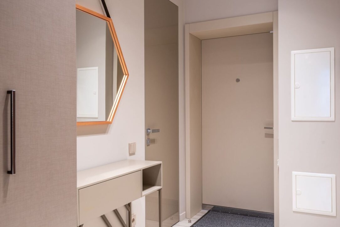 Entré med minimalistisk dør, skjult karm, speil og integrert oppbevaring